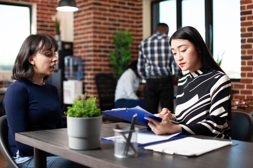 Asian,Recruiter,Reviewing,Clipboard,And,Guiding,Caucasian,Female,Candidate,Through Skillsfishing
