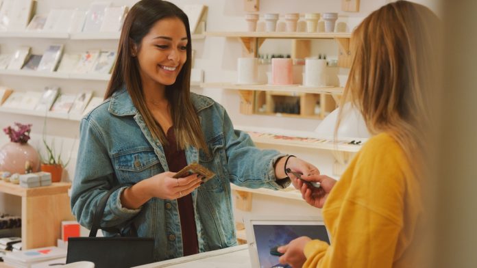 Female,Customer,Paying,Sales,Assistant,At,Checkout,Of,Gift,Store Carlo focus